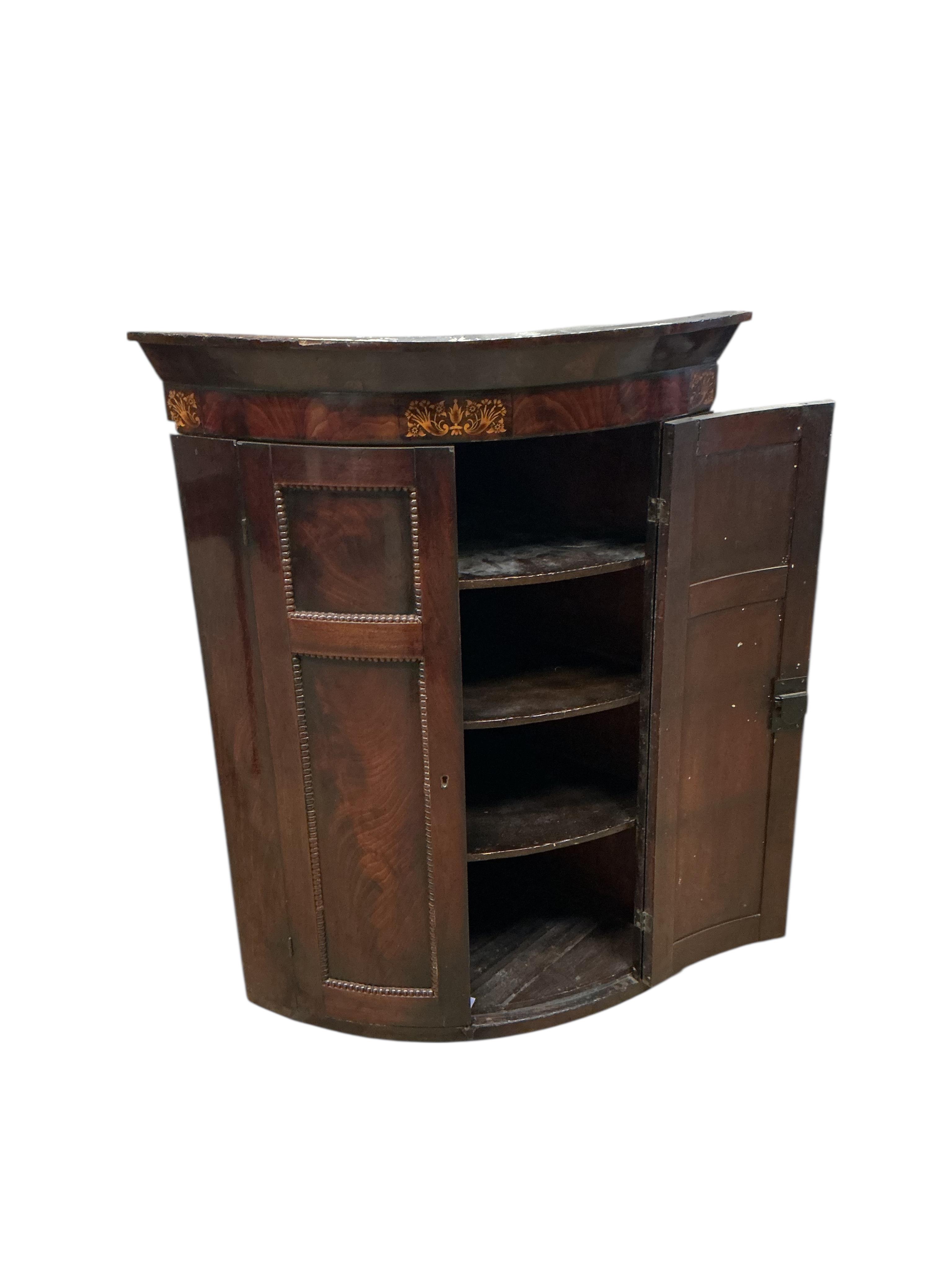 A George IV inlaid mahogany bow fronted hanging corner cupboard, width 80cm, depth 54cm, height 108cm